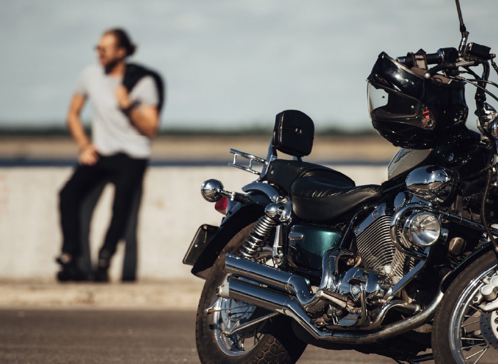 Hombre-joven-mirando-al-horizonte-y-moto-estacionada 