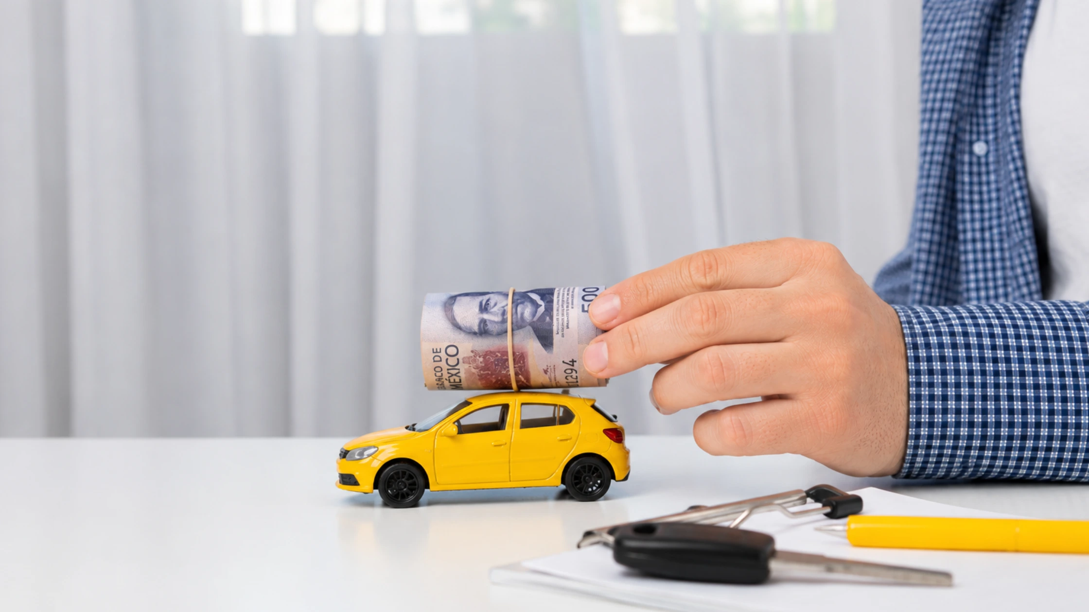 Mano-de-hombre-sosteniendo-fajo-de-billetes-sobre-carro-de-juguete