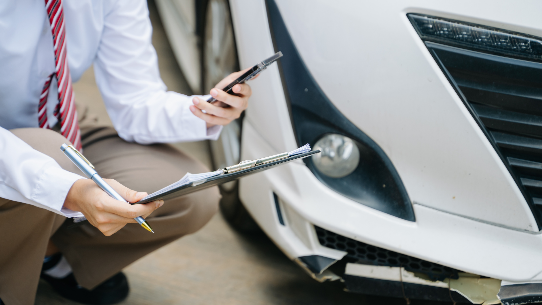 Un-asesor-de-seguros-automotriz-se-encuentra-agachado-inspeccionando-el-daño-en-el-automóvil